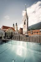 a church with a clock tower and a swimming pool at ADLER Historic Guesthouse in Bressanone