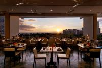 a restaurant with tables and chairs and a view of the city at The Ritz-Carlton Residences, Waikiki Beach Hotel in Honolulu