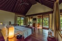a bedroom with a bed in a room with windows at Qunci Villas Resort in Senggigi