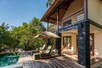 a patio with chairs and an umbrella next to a swimming pool at Qunci Villas Resort in Senggigi