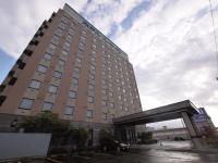 un edificio alto con un coche aparcado delante de él en Hotel Route-Inn Shibata Inter, en Shibata