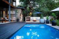 Una mujer parada junto a una piscina en un patio trasero. en Rafiki Bush Lodge, en Hoedspruit