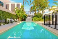 Una piscina en un patio con sillas y un edificio. en Fletcher Lane Boutique Stay Byron Central, en Byron Bay
