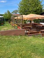 een speeltuin met tafels en een parasol in een veld bij Gasthaus Bellevue in Wandlitz