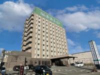Un gran edificio con un cartel encima. en Hotel Route-Inn Tsuruoka Ekimae, en Tsuruoka