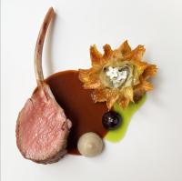 Un trozo de carne y una flor en un plato blanco. en Hôtel de Tourrel, Saint Rémy de Provence, a Member of Design Hotels, en Saint-Rémy-de-Provence