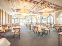 Un comedor con mesas y sillas y ventanas. en Hof Weissbad Health & Wellness Resort, en Weissbad