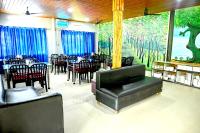 a restaurant with tables and chairs and a large mural at Rahaman Farm House in Lataguri