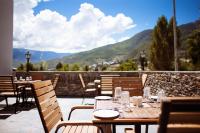Un patio con mesas y sillas con montañas al fondo. en Hotel Osel, en Thimphu