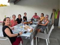 een groep mensen die rond een tafel zitten met eten bij Aux Belles Vacances - ADULTS ONLY in Caux-et-Sauzens