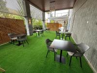 un patio con mesas, sillas y césped verde en Hotel Next, en Masaka