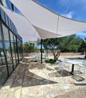 eine Terrasse mit einem weißen Sonnenschirm sowie Tischen und Stühlen in der Unterkunft ANDESA Mobile Home Pirovac- Perfect vacation in a campsite with a pool, few steps from the sea! in Pirovac