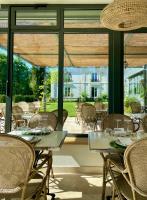 a dining room with tables and chairs and a large window at Les Hayes en Sologne in Fontaines-en-Sologne