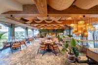 Un comedor con mesas y sillas y plantas. en White Wharf Beach Resort Morjim Goa, en Morjim