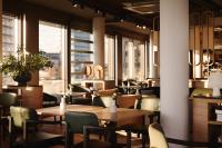 ein Restaurant mit Tischen, Stühlen und Fenstern in der Unterkunft A by Adina Vienna Danube in Wien