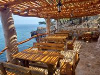 a group of wooden benches sitting under a wooden umbrella at Apartmani Nikola in Zastražišće