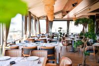 een restaurant met witte tafels, stoelen en ramen bij Amsterdam Hotel in Belgrado