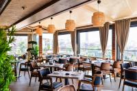 een restaurant met tafels en stoelen en grote ramen bij Amsterdam Hotel in Belgrado