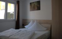ein Schlafzimmer mit einem Bett mit weißen Laken und einem Fenster in der Unterkunft Ferienpark Rübezahl am Müggelsee, Haus 21 Efeu mit eigener Sauna, idealer Ort für Natur- und Erholungssuchende, für Radfahrer, Familien mit Kindern und Hundeliebhaber in Berlin
