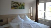 ein Schlafzimmer mit einem Bett mit weißen Laken und einem Fenster in der Unterkunft Ferienpark Rübezahl am Müggelsee, Haus 20 Mohn mit eigener Sauna, idealer Ort für Natur- und Erholungssuchende, für Radfahrer und Familien mit Kindern in Berlin