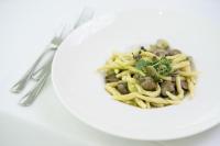 a white plate with pasta and mushrooms on a table at Hotel Balance in Milano Marittima