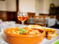 eine Schüssel Essen auf einem Teller mit einem Glas Wein in der Unterkunft Gîte Zelai Begi in Aldudes