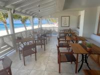 restauracja ze stołami i krzesłami oraz plaża w obiekcie Hôtel Le Roy w mieście Christ Church