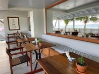 restauracja z drewnianymi stołami i widokiem na ocean w obiekcie Hôtel Le Roy w mieście Christ Church