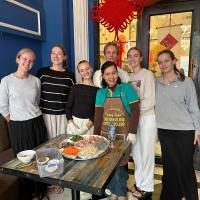 Un grupo de personas de pie alrededor de una mesa con comida. en Little Charm Hanoi Hostel, en Hanói