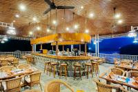 un restaurant avec un bar avec tables et chaises dans l'établissement Riverside Springs Resort, à Chitwan