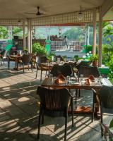 un restaurant vide avec des tables et des chaises sur une terrasse dans l'établissement Riverside Springs Resort, à Chitwan