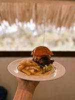 una persona che tiene un piatto con un panino e patatine fritte di Kokos Resort Mentawai a Pulau Masokut