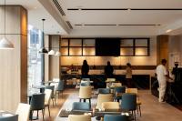 people standing in a restaurant with tables and chairs at Hotel Grand Chancellor Auckland in Auckland