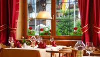 uma mesa em um restaurante com cortinas e janelas vermelhas em Steinbach-Hotel em Ruhpolding