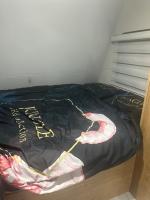 ein Bett mit einer schwarzen Bettdecke mit dem Wort „Hotel“ darauf in der Unterkunft קרוואן על הים in Eilat