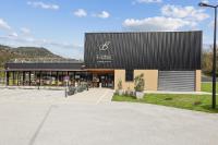 a hotel with a black roof and a parking lot at Hôtel Restaurant AKENA Molinges - La Brocatelle in Saint-Claude