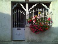 a door with two flower baskets and a gate with flowers at Riverside Home Cottage in Trèbes