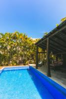 a blue swimming pool with a pergola and palm trees at Pousada Vila Tamarindo Eco Lodge in Florianópolis