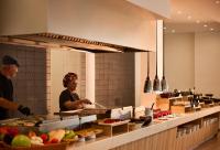 uma mulher em pé na cozinha preparando comida em Sunrise Hotel em Pefki Rhodes