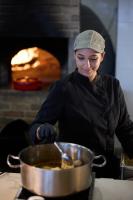Uma mulher preparando comida em uma panela no fogão. em Sunrise Hotel em Pefki Rhodes