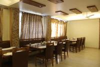 ein Esszimmer mit Tischen, Stühlen und Fenstern in der Unterkunft Sunny International in Mahabaleshwar