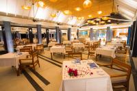 Un comedor con mesas y sillas blancas. en Furaveri Maldives - COMPLIMENTARY ROUND-TRIP SEAPLANE TRANSFER FOR TWO FOR A MINIMUM OF 5 NIGHTS OR MORE FOR STAYS 1ST MAY 2026 TO OCTOBER 31ST 2026, en Raa Atoll