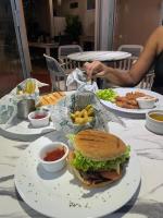 Una mesa con platos de comida y un sándwich y patatas fritas. en Hotel Neptuno Refugio, en Boca Chica
