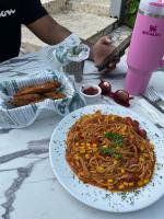 Una mesa con un plato de espaguetis y algo de comida. en Hotel Neptuno Refugio, en Boca Chica