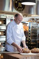 Un hombre de pie en una cocina preparando hogazas de pan. en Appellation Lodi - Wine & Roses Resort and Spa, en Lodi