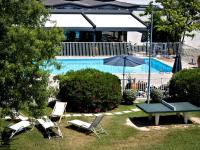 una piscina con sillas, una mesa y una sombrilla en ibis Styles Avignon Sud, en Aviñón