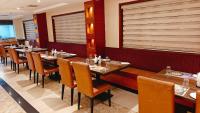 a dining room with wooden tables and chairs at MM Legacy - A Bergamont Hotel, Kanchipuram in Kanchipuram