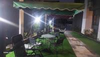 Un patio con mesa y sillas y un toldo verde. en Hotel Padelia Apartment Airport Road Lagos, en Lagos