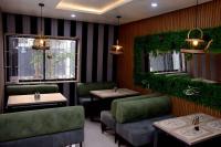 Un restaurante con sillas y mesas verdes y ventanas. en Hotel Padelia Apartment Airport Road Lagos, en Lagos