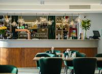 a restaurant with green chairs and a bar at Hotel Poem - Roof Top Pool & Panoramic Sea View in Eforie Nord